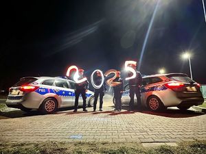 noc, radiowozy, policjanci stoją obok, cyfra 2025