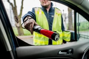 policjant z urządzeniem do badania trzeźwości, zdjęcie z pozycji kierowcy samochodu, dzień, pochmurno