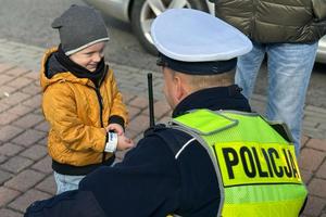 policjant w przysiadzie, rozmawia z małym dzieckiem, dzien, dziecko się usmiecha