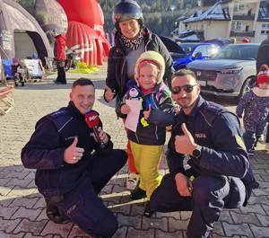 zdjęcie -dzień, słonecznie, policjanci pozują do zdjęcia z dzieckiem i opiekunką