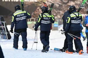 policjanci idą po śniegu, niosą narty na ramieniu, dzień