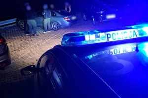 policyjny radiowóz, noc, policjanci kontrolują osoby