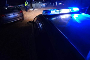 policyjny radiowóz, noc, policjanci kontrolują osoby
