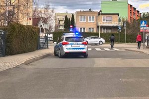 dzień , policyjny radiowóz z włączonymi sygnałami świetlnymi stoi na drodze