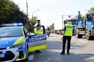 dzień, droga, policjanci przy radiowozie obserwują ruch pojazdów