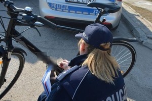 policjantka w przysiadzie ogląda rower, droga, dzień