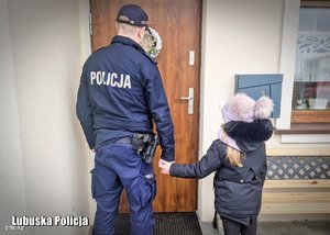 policjant prowadzi do domu dziecko za rękę