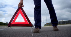 osoba ustawia trójkąt ostrzegawczy na jezdni, dzień, droga