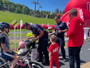 dzień, pogoda słoneczna, policjanci i dzieci w miasteczku ruchu, dzieci na rowerach, hulajnogach, rozmawiają z policjantami