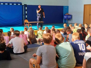 sala gimnastyczna, policjant przemawia do dzieci