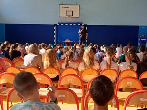 sala gimnastyczna, policjant przemawia do dzieci