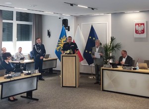 policjant przemawia zza mównicy na sali sesyjnej