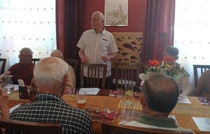 osoby zgromadzone na sali siedzą na krzesłach przy stole , rozmawiają , śmieją się
