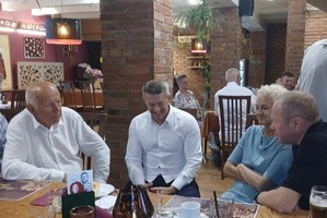 osoby zgromadzone na sali siedzą na krzesłach przy stole , rozmawiają , śmieją się