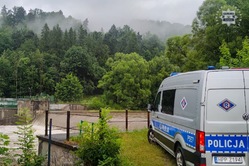 radiowóz, deszcz, w tle polana