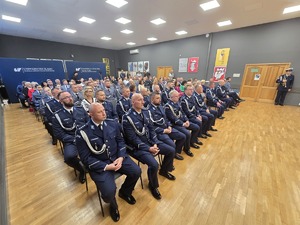 osoby zgromadzone na sali, siedzą i obserwuja sceną