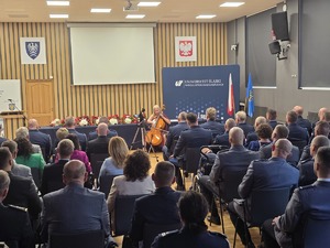 osoby zgromadzone na sali, siedzą i obserwuja sceną