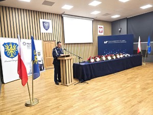 osoba stoi za mównicą i przemawia do zgromadzonych gości