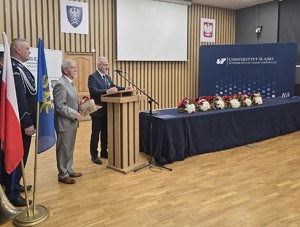 osoba stoi za mównicą i przemawia do zgromadzonych gości