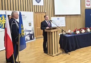 osoba stoi za mównicą i przemawia do zgromadzonych gości