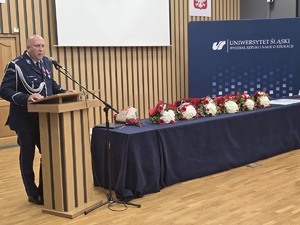 osoba stoi za mównicą i przemawia do zgromadzonych gości