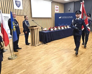 osoba stoi za mównicą i przemawia do zgromadzonych gości