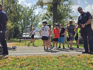 słonecznie, park, policjanci uczą dzieci jeździć na hulajnogach