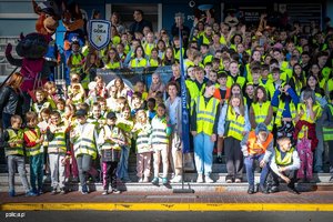 dzieci pozują do zdjęcia w kamizelkach odblaskowych