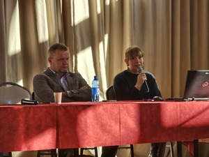 zdjęcia z sali, prelegenci przemawiają, osoby zgromadzone siedzą na krzesłach i słuchają ,