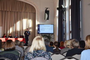 zdjęcia z sali, prelegenci przemawiają, osoby zgromadzone siedzą na krzesłach i słuchają ,