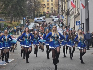 osoby maszerują, dużo flag Polski, pochmurno, widać poczet sztandarowy