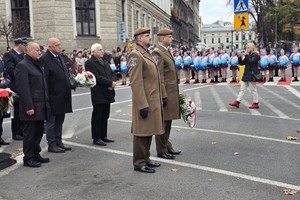 osoby maszerują, dużo flag Polski, pochmurno, widać poczet sztandarowy