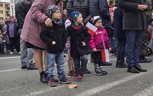 osoby maszerują, dużo flag Polski, pochmurno, widać poczet sztandarowy
