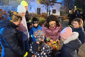 Anna Grygierek rozdaje odblaski, ciemno, usmiechnięte dzieci