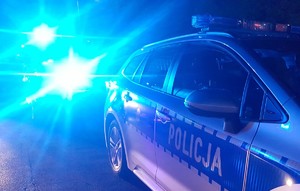 radiowóz policji, w tle pojazd z włączonymi światłami błyskowymi