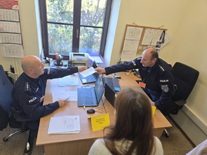 policjanci podają sobie dokument