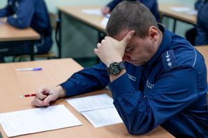 policjanci siedzą przy ławkach i piszą test