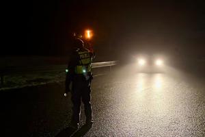 policjant zatrzymujący w nocy pojazd n drodze