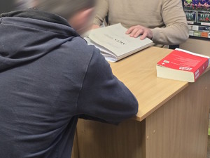 mężczyzna siedzi przy biurku, przed nim kodeks karny