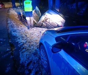 noc, droga, pojazd w rowie, policjant przy nim, oświetlają go światła radiowozu