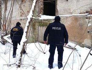 policjant i strażnik miejski przy pustostanie, sprawdzają, zima, dzień, snieg