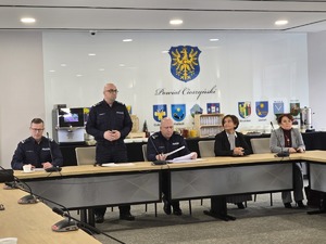 sala sesyjna, sztuczne światło, samorządowcy i policjanci zgromadzeni na sali siedzą i oglądają prezentację