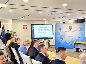 sala sesyjna, sztuczne światło, samorządowcy i policjanci zgromadzeni na sali siedzą i oglądają prezentację