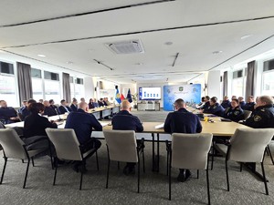 sala sesyjna, sztuczne światło, samorządowcy i policjanci zgromadzeni na sali siedzą i oglądają prezentację