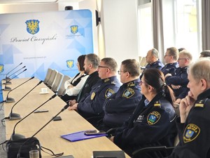 sala sesyjna, sztuczne światło, samorządowcy i policjanci zgromadzeni na sali siedzą i oglądają prezentację