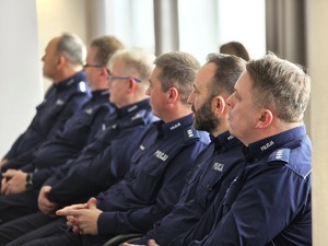 sala sesyjna, sztuczne światło, samorządowcy i policjanci zgromadzeni na sali siedzą i oglądają prezentację