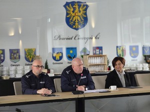 sala sesyjna, sztuczne światło, samorządowcy i policjanci zgromadzeni na sali siedzą i oglądają prezentację