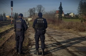zdjęcie -policjant i strażnik służby ochrony kolei na peronie, w tle torowisko