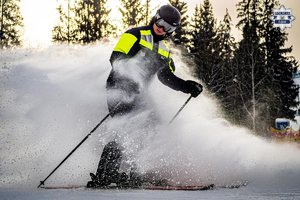 policjant na nartach, zima, śnieg, jasno, gwałtowanie hamuje, śnieg unosi się w powietrzu
