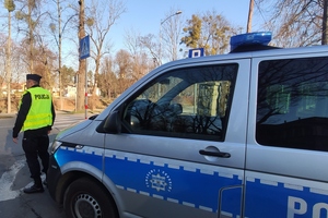 policjant przed radiowozem, dzień, droga